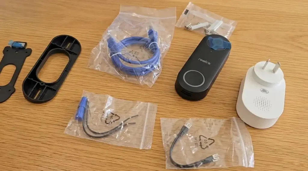 Unboxing the Reolink video doorbell without subscription showing all included hardware, mounting plates, and chime.